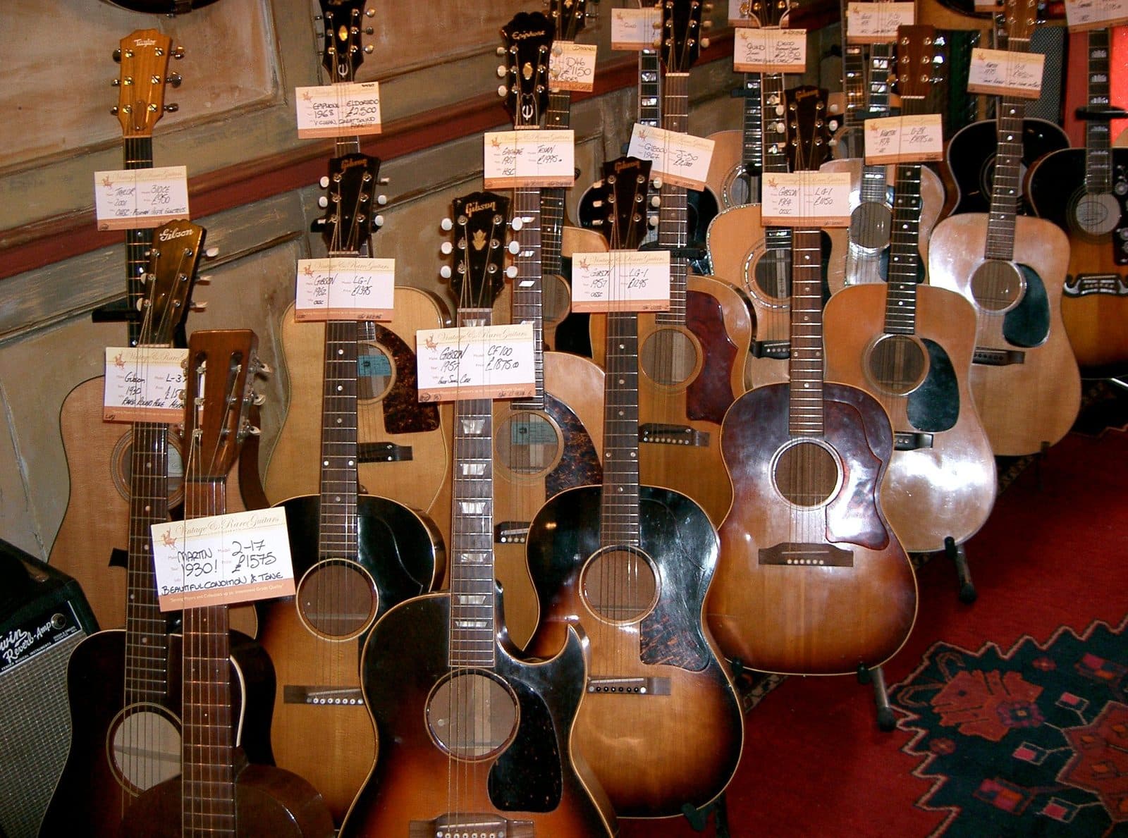 A wall of vintage acoustic guitars for sale in a shop.