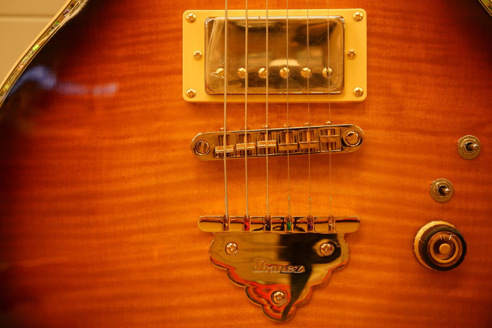 Close-up of an Ibanez electric guitar's bridge, pickup, and strings.