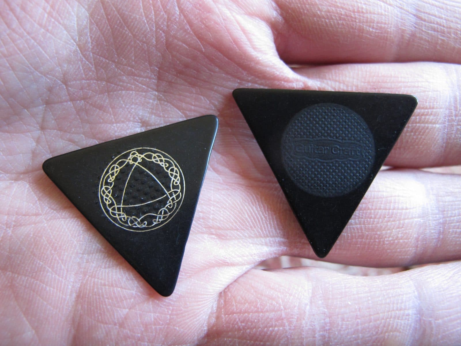 Two triangular guitar picks held in a palm.