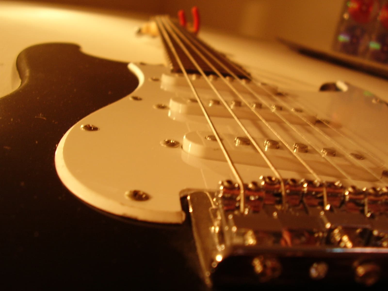 Low-angle close-up of an electric guitar showing the strings passing over the single-coil pickups and bridge.