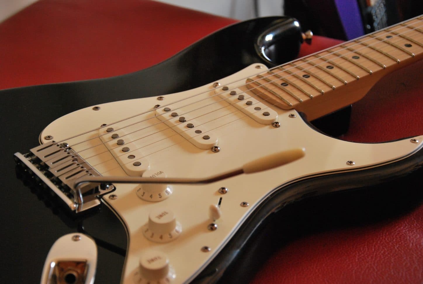 Close-up of a black Fender Stratocaster body showing its contoured double-cutaway shape and three single-coil pickups, the design at the center of Fender's copyright dispute with Thomann